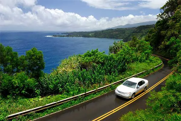 White car driving on a highway in Maui. 