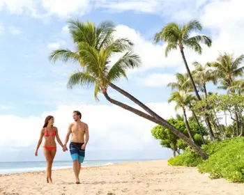 A couple walking along a Maui beach during the day.