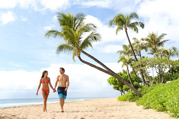 A couple walking along a Maui beach during the day. 