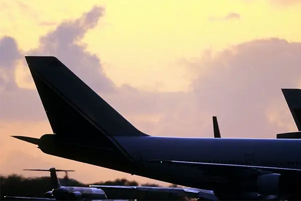 Tailfin of a plane on a tarmac at sunset. 