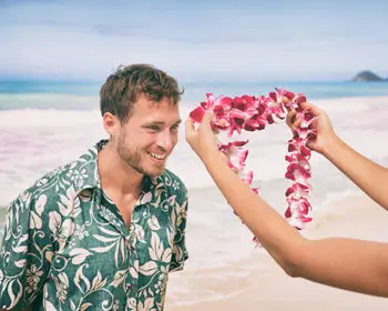 Man receives a lei flower garland on the beach in Hawaii.