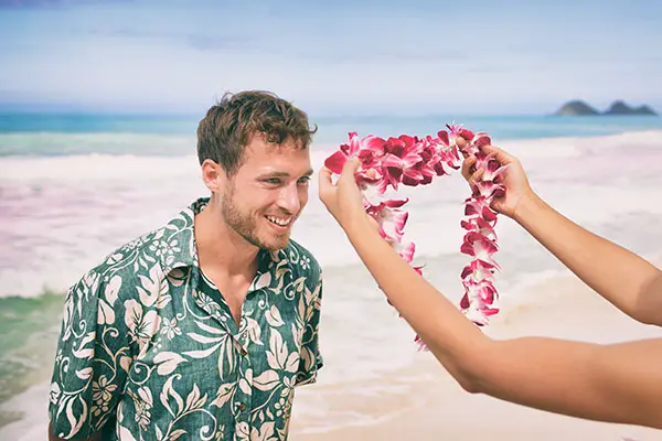 Man receives a lei flower garland on the beach in Hawaii. 