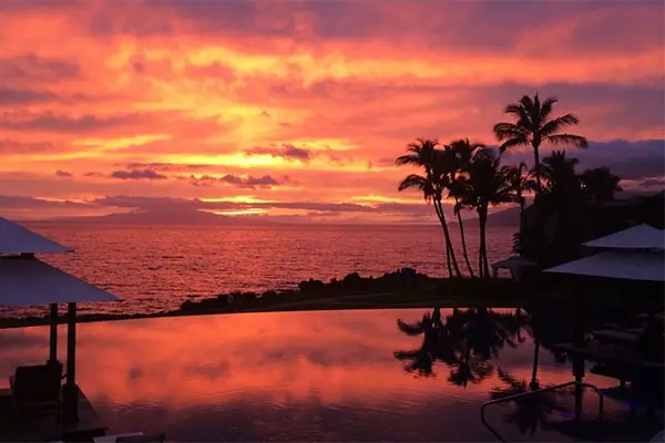 Orange and golden sunset from a cabana-side pool overlooking the ocean.  