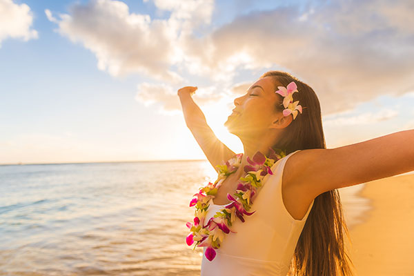 Woman wearing a lei flower necklace on the beach. 