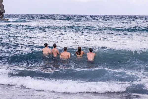 Five people standing in the ocean's tide up to their waist.
