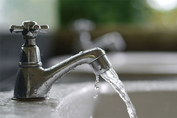 Sink faucet turned on so that water streams into the sink. 