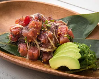 Poke on a wooden plate with sliced avocado.