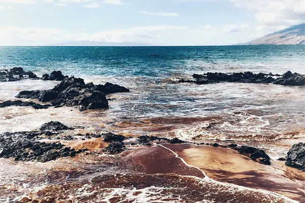 Beach of rocks and sand in Kihei, Maui.