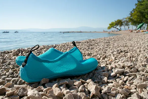 Blue water shoes on a pebble beach. 
