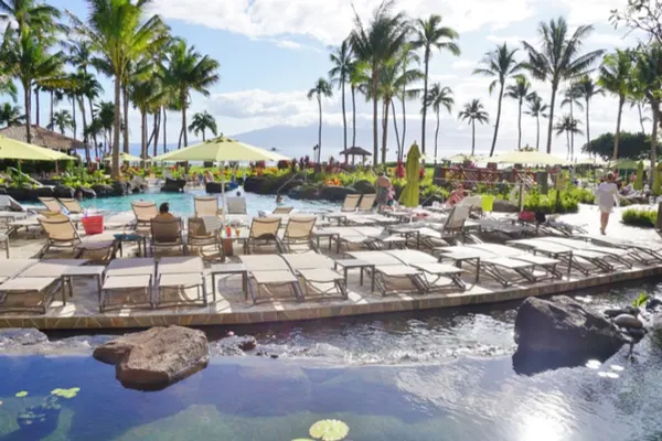 Timeshare pool in Maui with lounge chairs and palm trees. 