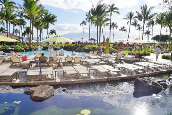 Timeshare pool in Maui with lounge chairs and palm trees.