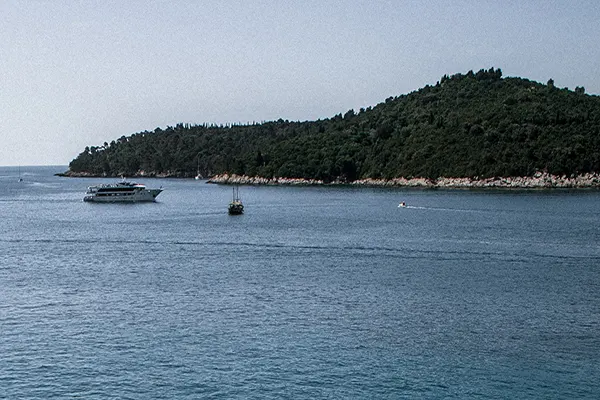 View of the ocean with an island in the background, boats on the water.