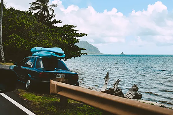 Car parked on the side of the road over the ocean.