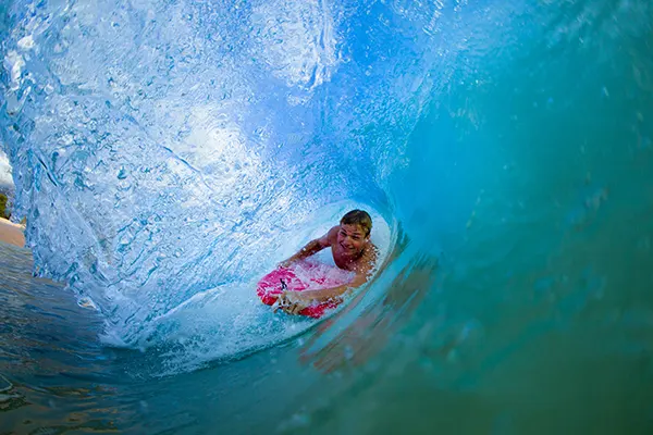 Person boogie boarding through funnel of water. 