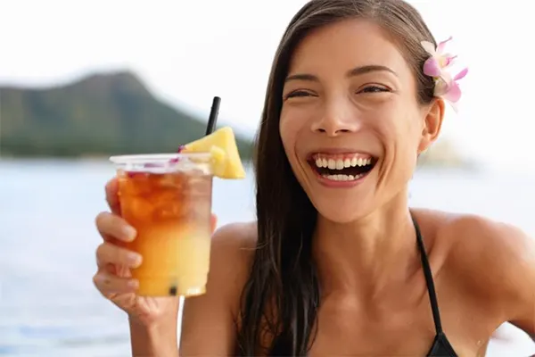 Woman with a big smile holding a drink. 