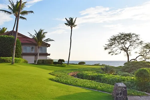 Resort in Maui with the ocean in the background, a clean green lawn.