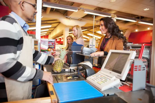 A cashier at the grocery store helping a customer at checkout. 