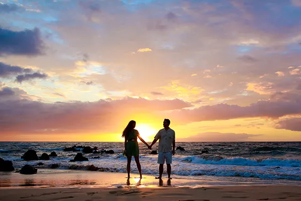 Silhouette couple holding hands on the beach at sunset