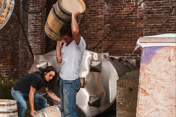 Man carrying barrel ion his shoulder n distillery. 