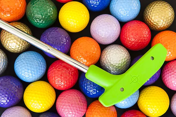 Green mini golf putter with balls of assorted colors