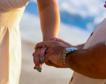 People holding hands on the beach, at a marriage ceremony.