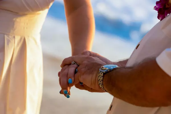 People holding hands on the beach, at a marriage ceremony.