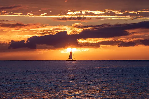 Scenic sunset viewed from Lahaina harbor, Maui, Hawaii. A silhouette of sail boat against setting sun