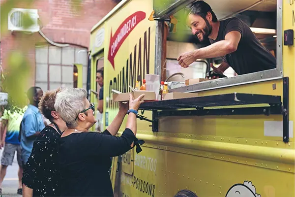 Man handing woman food from food truck. 