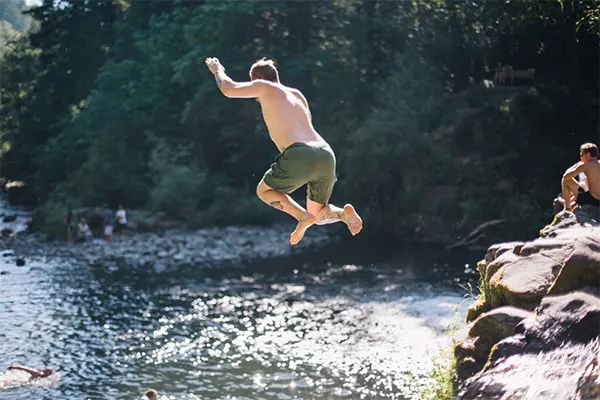 Man cliff jumping into a natural pool. 