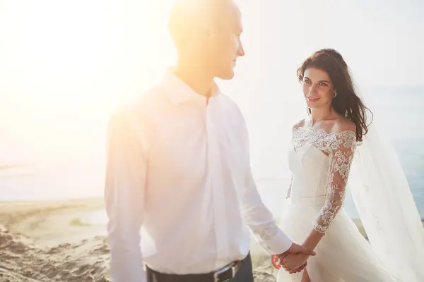 A wedding couple holding hands at the beach. 