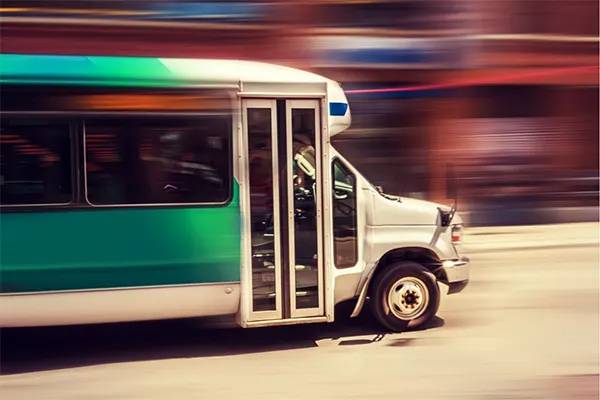 A green shuttle bus on the road.