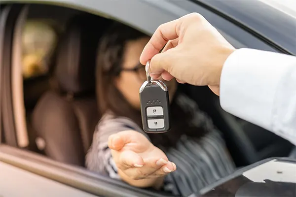 Woman receiving keys for her rental car. 