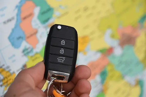 Hand holding key in front of a world map. 