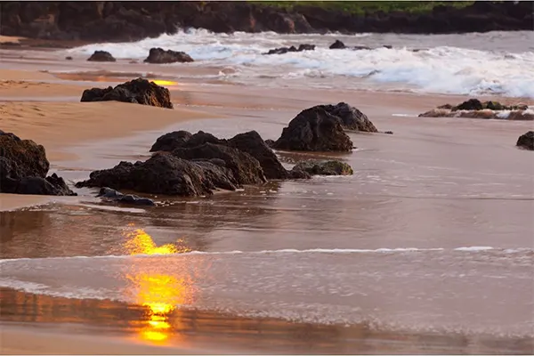 Rocks along the beach with the tide in the background.