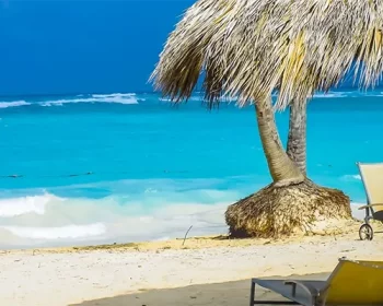 Beach with palm cabana and beach chairs
