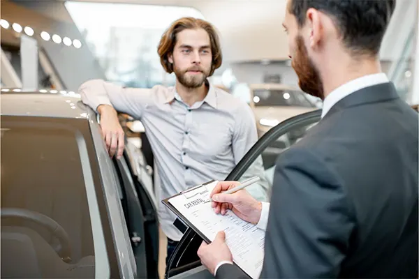 Man with clipboard explaining car rental process. 