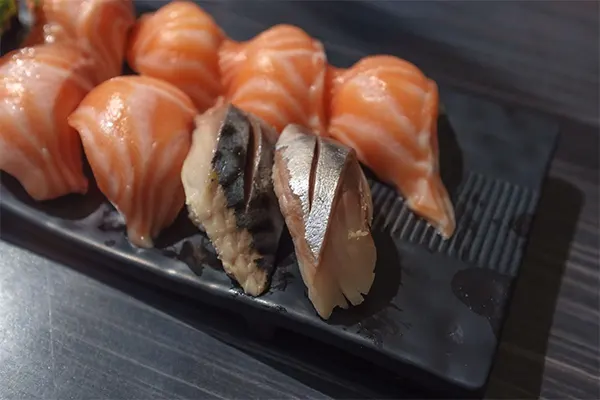 Close up shot of salmon sashimi on a black plate. 