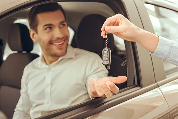 Man accepting keys while sitting in the driver's seat in the car. 