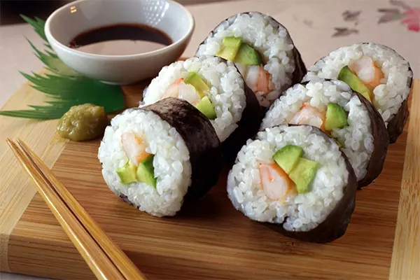 Sushi rolls on a wooden plate with chopsticks
