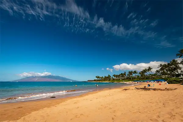 Mokapu Beach during the day with a deep blue sky and a gentle tide.