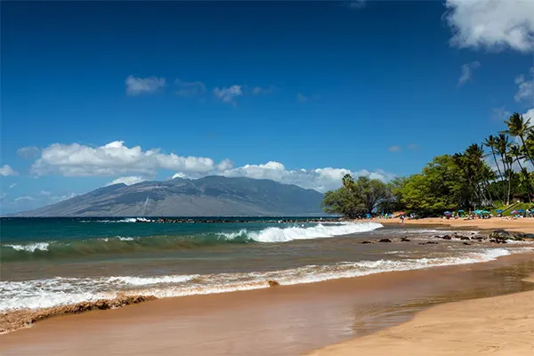 Ulua Beach on a sunny day, gentle waves lapping the sands. 