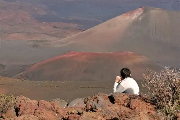 Man sitting on rocks at Pele's Paint Pot in Maui, Hawaii. 