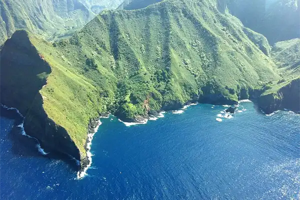 Aerial shot of Molokai, green mountains and blue ocean.