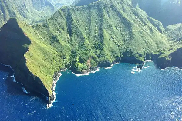 Aerial shot of Molokai, green mountains and blue ocean. 