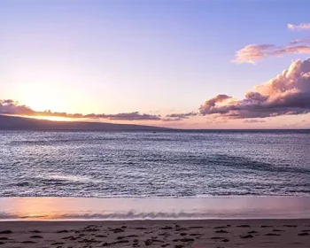 Kaanapali Beach at sunset, a gentle tide laps the beach.