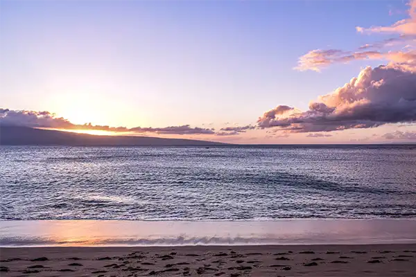 Kaanapali Beach at sunset, a gentle tide laps the beach.