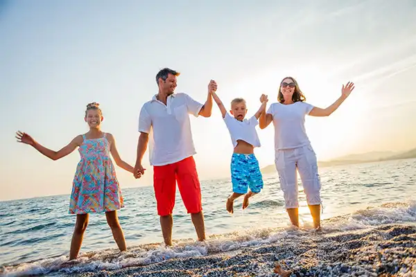 Family on a beach holding hands. 