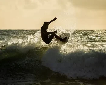 Man catching air on a wave in Maui at sunset.
