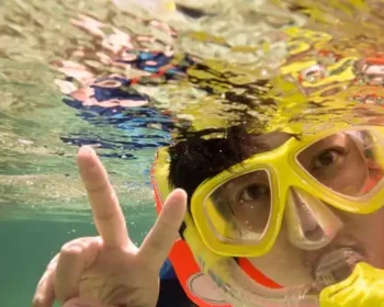 Boy snorkeling underwater and flashing the peace sign.