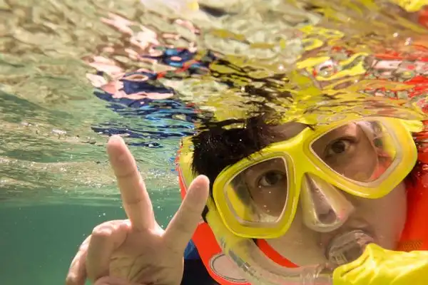 Boy snorkeling underwater and flashing the peace sign.